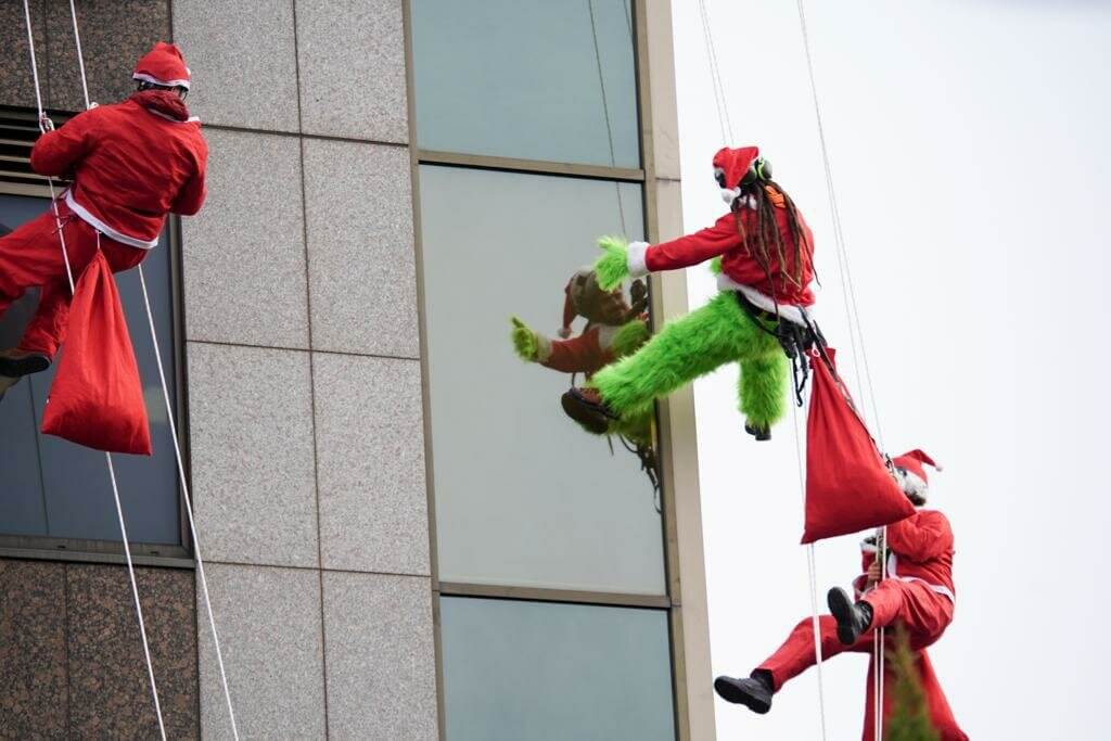 Rope Access volunteers dressed as Santa Claus and Grinch abseiling