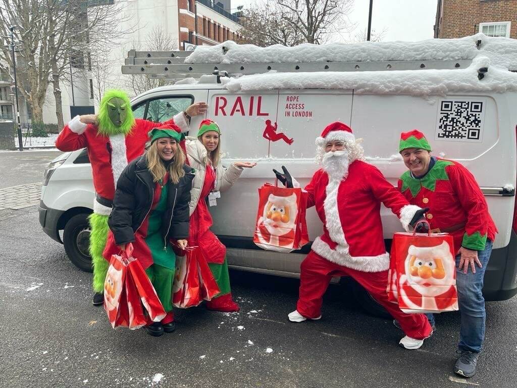 Rope Access volunteers dressed as Santa Claus, Grinch and elves with gifts for children