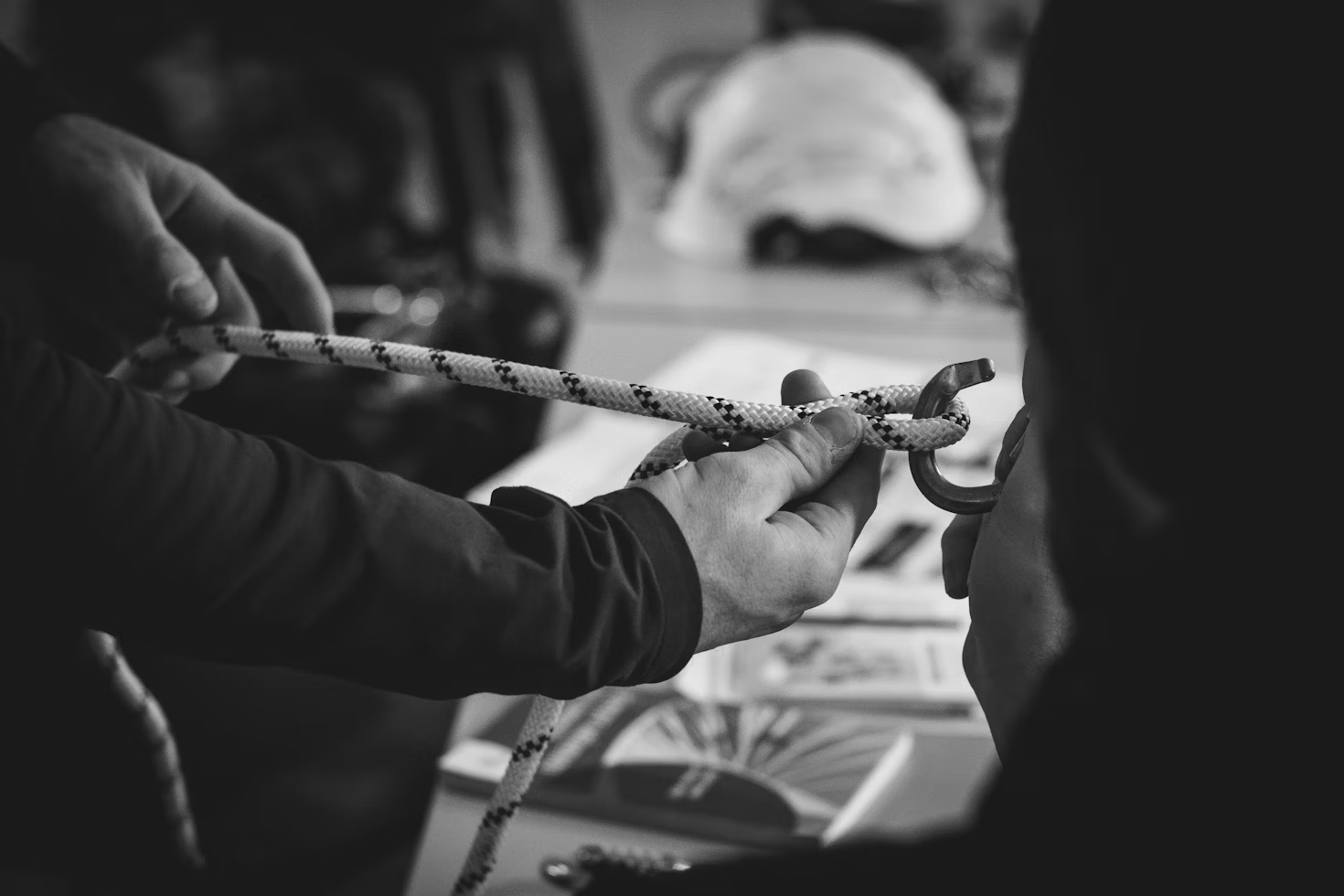 A close-up of hands tying a knot with rope and a carabiner for rope access training.