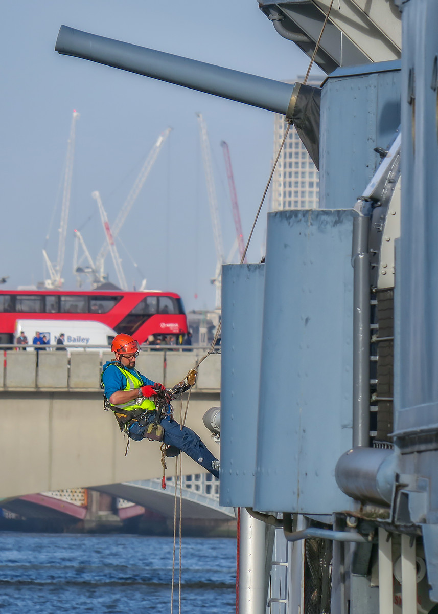 Rope access worker on a warship in London.