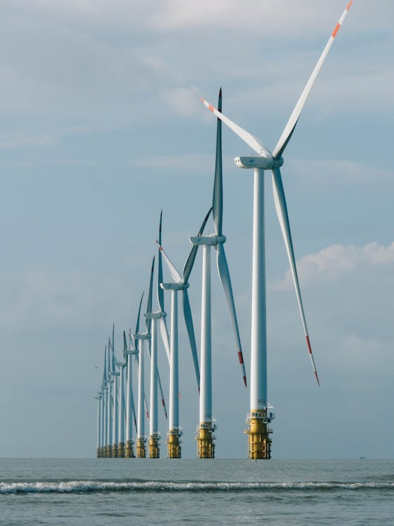 Row of offshore wind turbines standing in the sea under a cloudy sky.