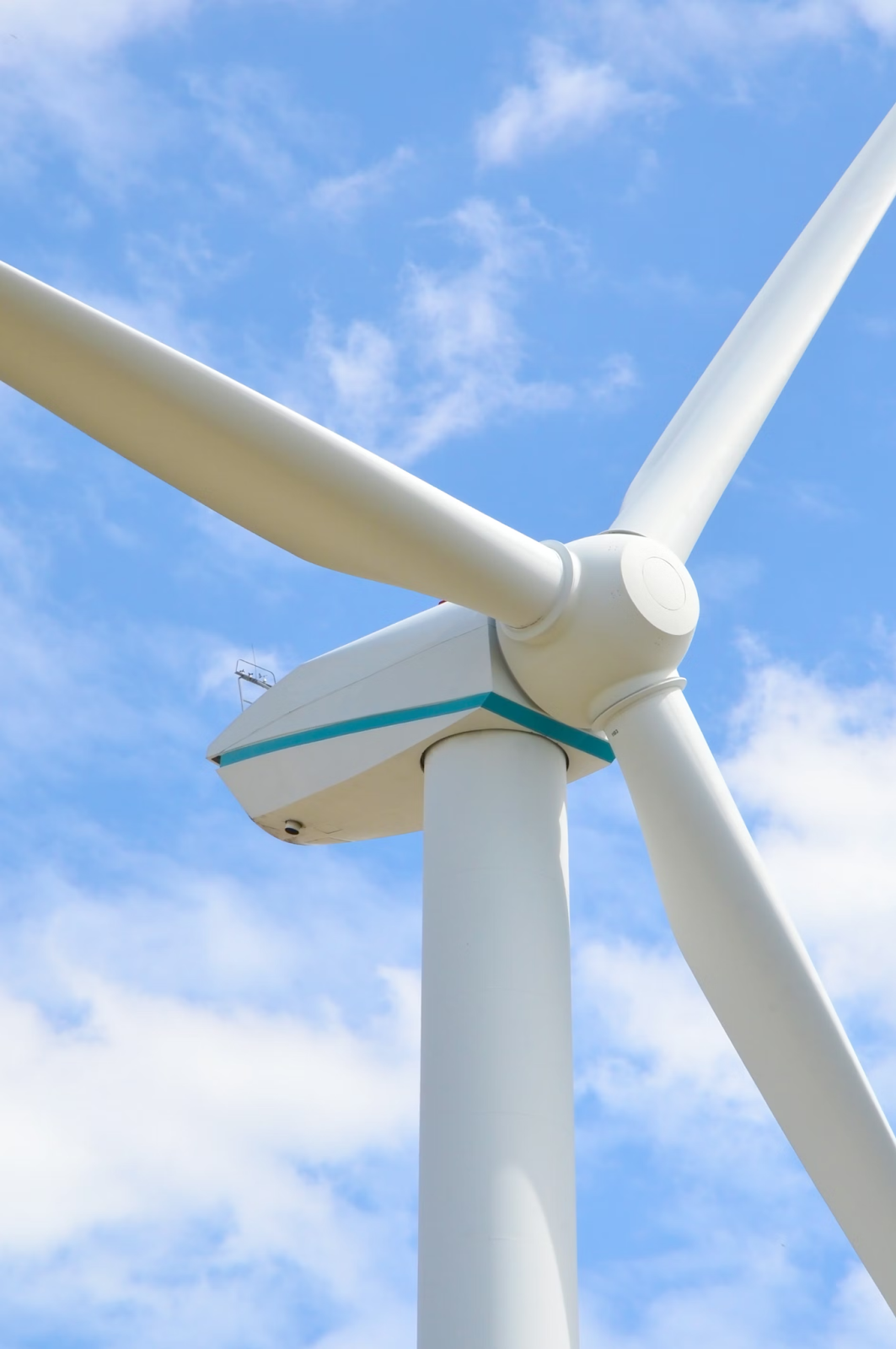White wind turbine with three blades against blue sky.